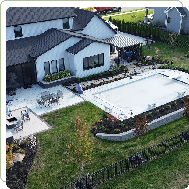 A backyard pool area with a covered pool and patio furniture.