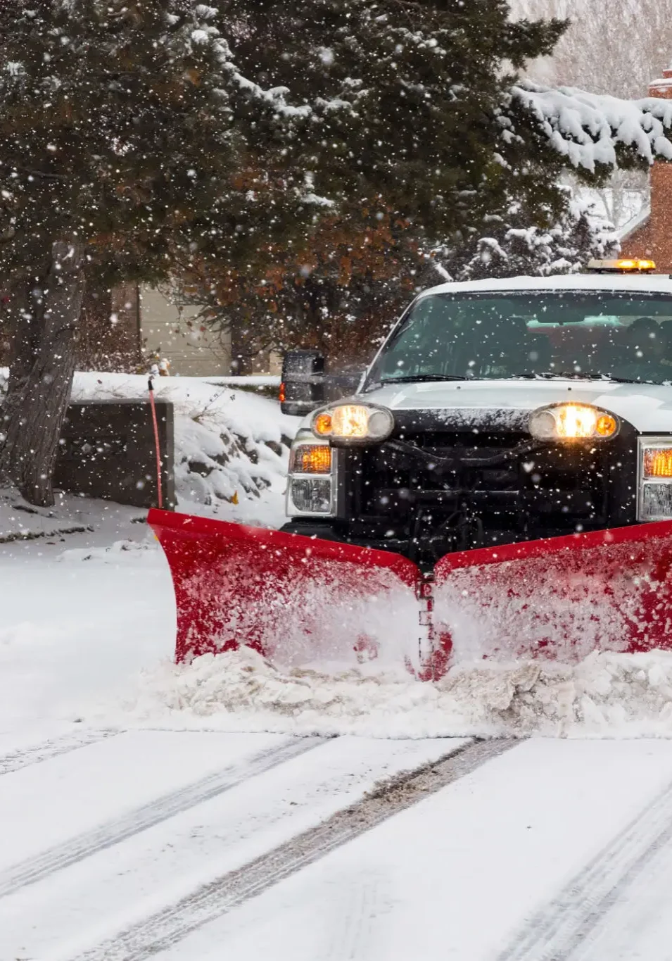 Truck plowing snow on a driveway.