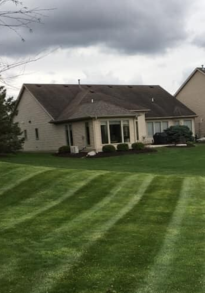 Well-maintained suburban house with a lush striped green lawn.